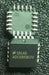 A black integrated circuit chip with white printed text reading 'S61AD ADC0858CIV' and multiple white pins around the edges, photographed on a dark textured surface.