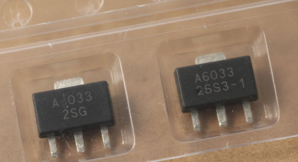 A close-up of a small electronic component in a clear plastic carrier tray, resting on a speckled gray countertop. The component has a black body with white printed text reading 'A803G' and '25C2-1'.