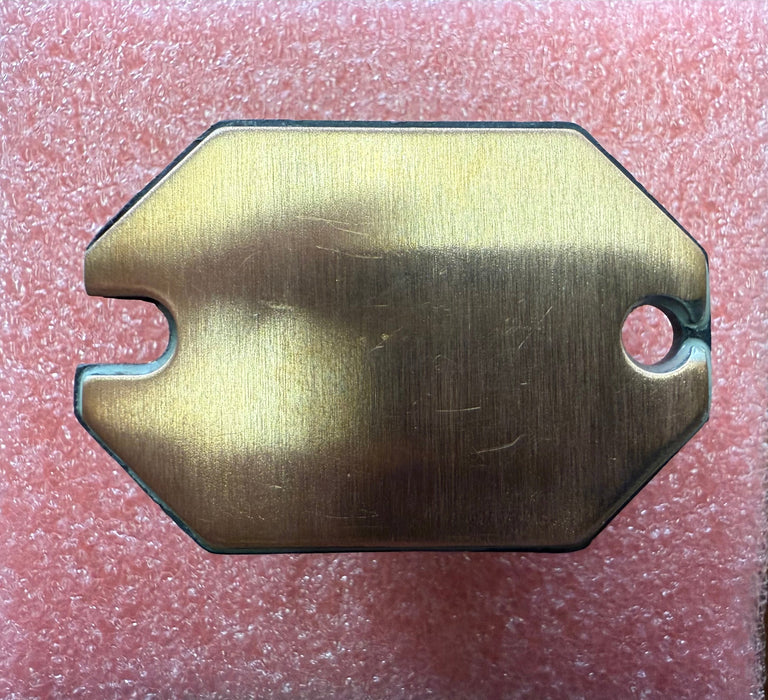 Brass-colored metal plate with a cutout on a red textured background