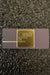 Analog Devices AD1674TD analog-to-digital converter chip in its original dark gray and gold packaging, resting on a textured black surface.