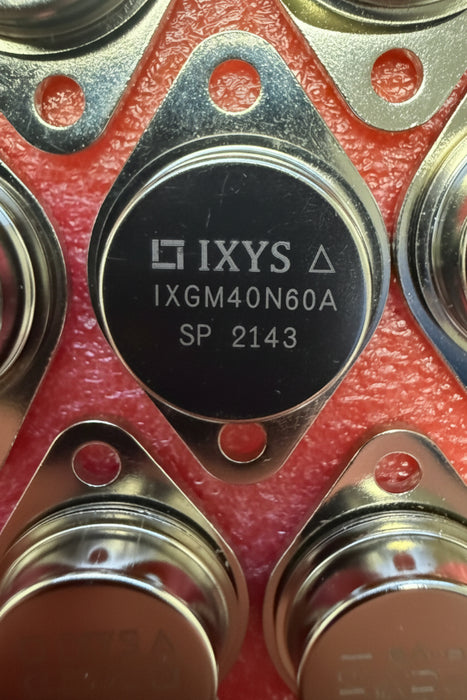 A close-up of a round black IXYS SP 2143 SOT-143 surface-mount transistor package on a red foam background.